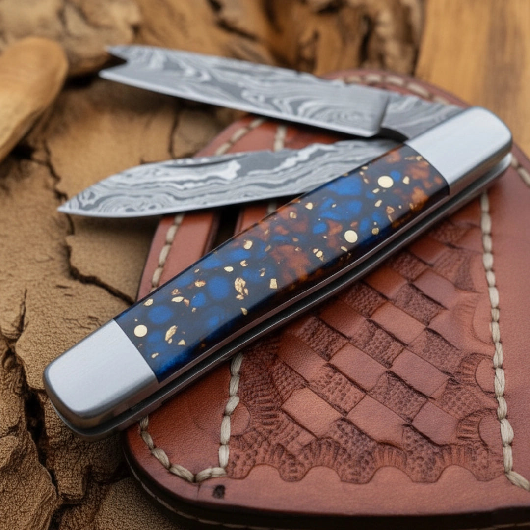 A detailed view of the blue resin handle of the 7.5-inch handmade Damascus folding bull cutter knife, highlighting the specks of gold and blue in the resin material.