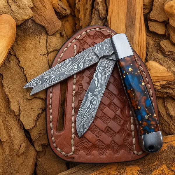 Folded knife with a decorative handle on a leather sheath against a wooden background