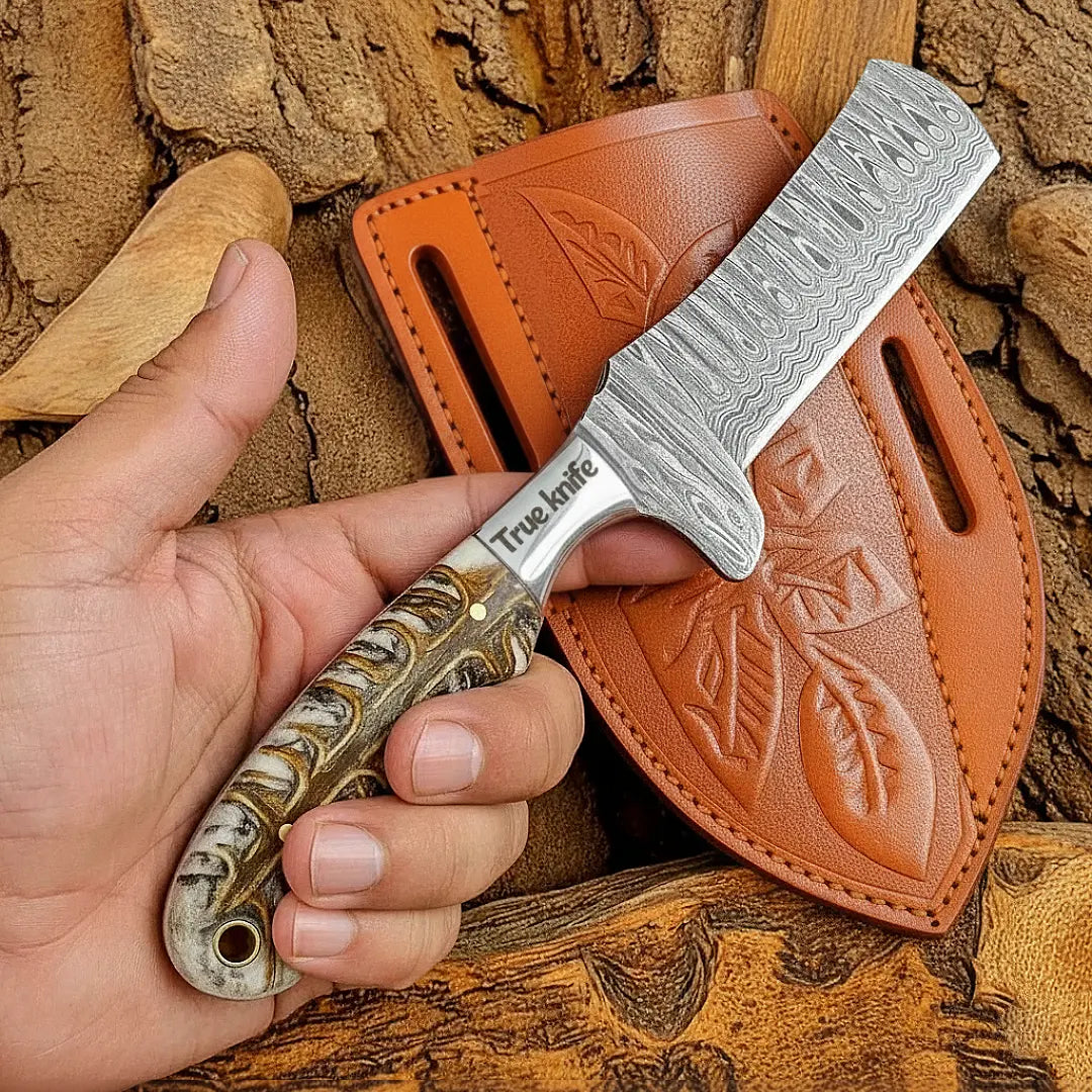 Hand holding a Bull Cutter Knife with a leather sheath against a wooden background