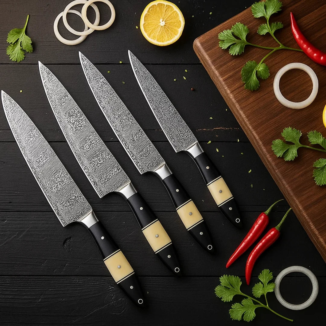 Set of four chef knives with black handles on a dark wooden surface with herbs and a lemon.