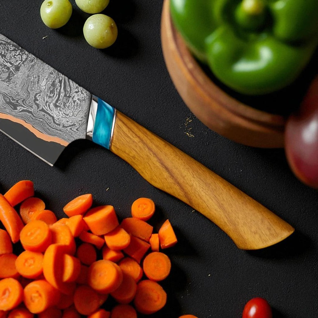 Wooden-handled knife with a decorative blade on a black surface with vegetables