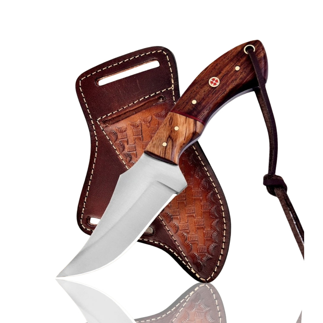 Handmade Cowboy Fixed Blade Knife with polished blade and two-tone wood handle, resting next to its brown leather sheath on a textured surface