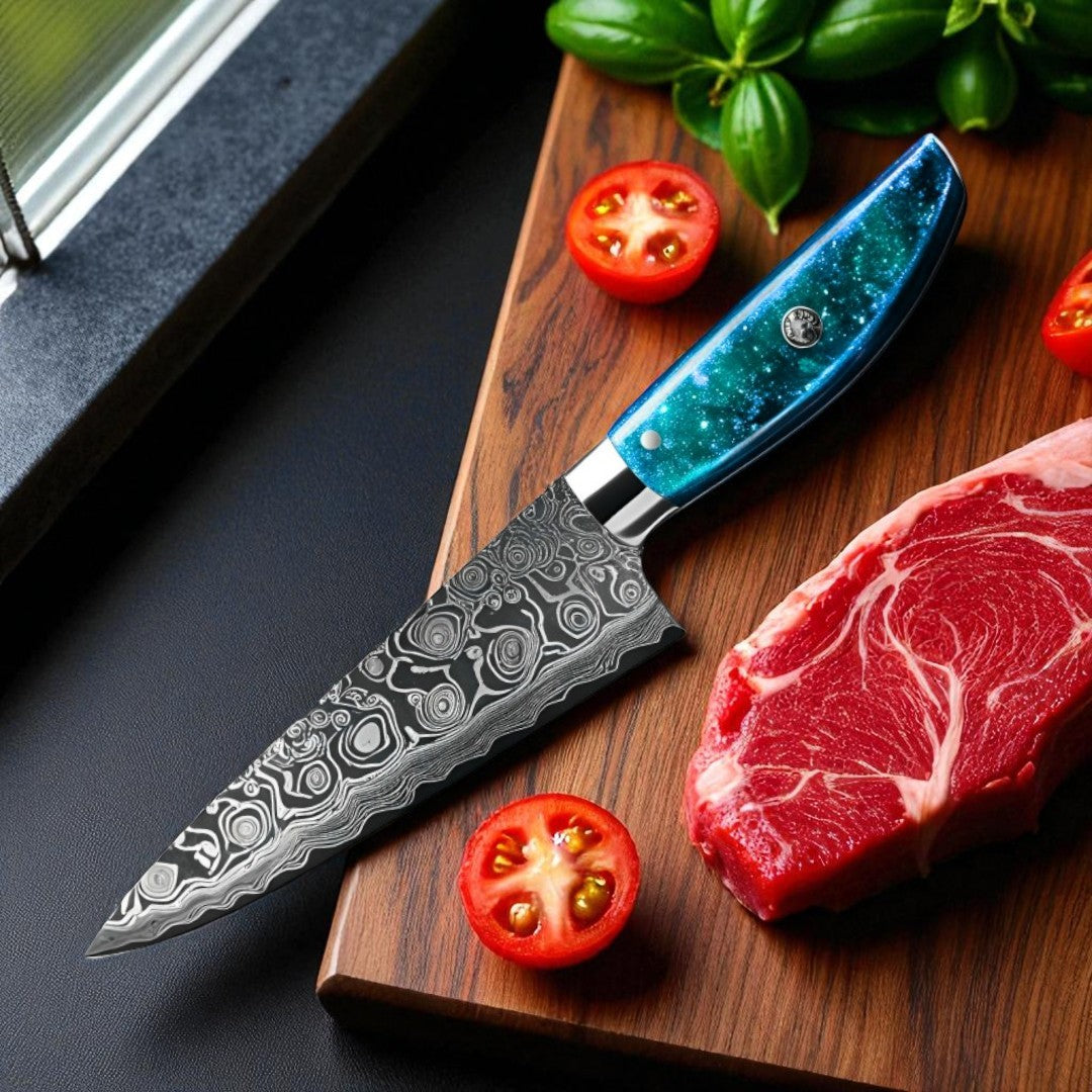 Kitchen chef's knife with a blue handle on a wooden cutting board with raw meat and tomatoes.