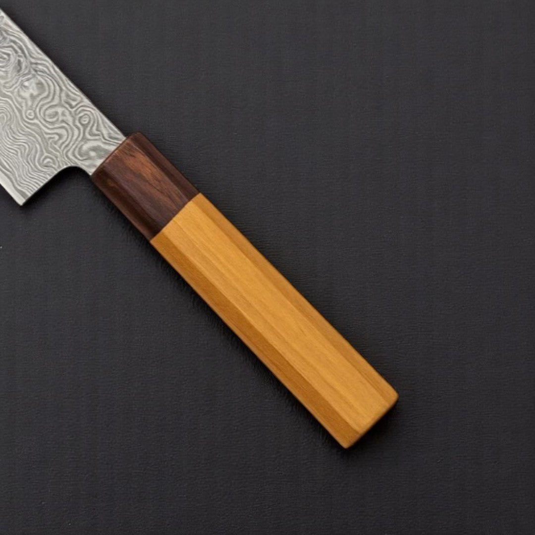 Japanese Damascus Santoku Knife with Wa-Handle on a dark surface next to sliced tomato and cucumber

