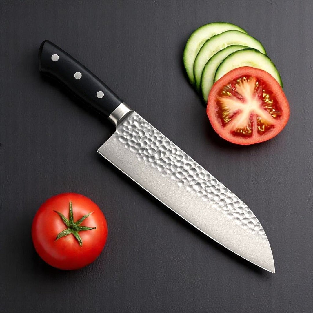 Close-up of Black Resin Handle on Hammered Santoku Knife next to sliced tomatoes and cucumber

