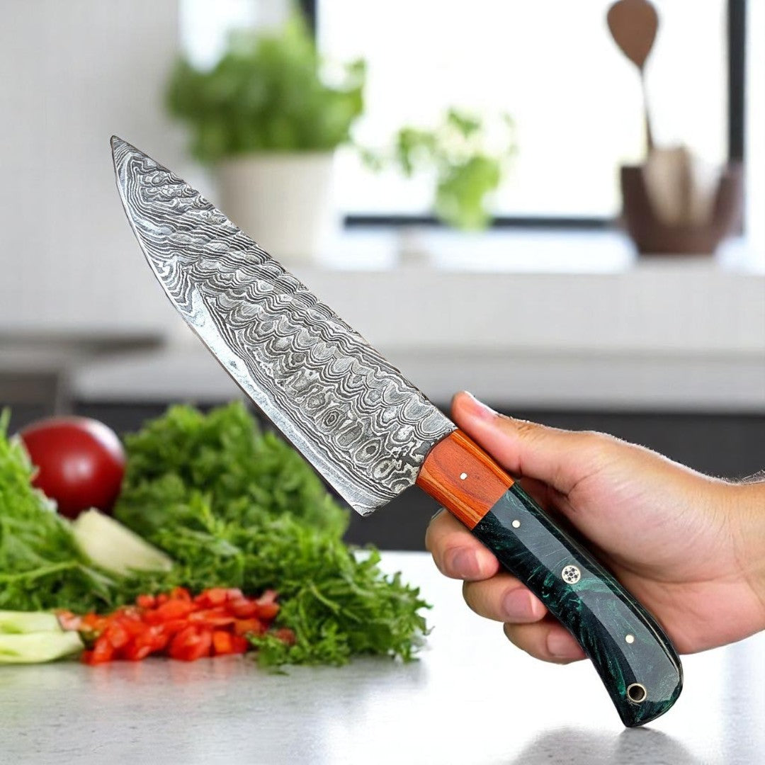 Damascus Chef Knife with green and black swirled resin and wood handle resting on a light countertop with fresh vegetables, ready for food preparation