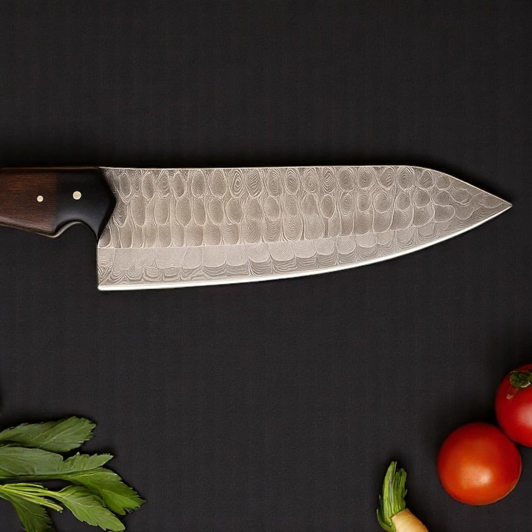 Damascus Chef Knife with Rosewood and G10 handle, angled on a dark surface with chopped vegetables