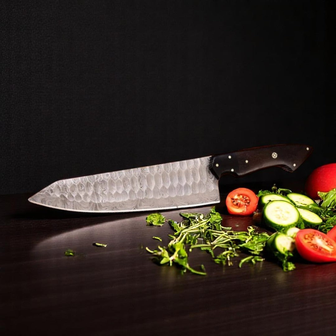  Overhead view of Damascus Chef Knife with Rosewood and G10 handle, showing full knife profile on a black surface with fresh vegetables

