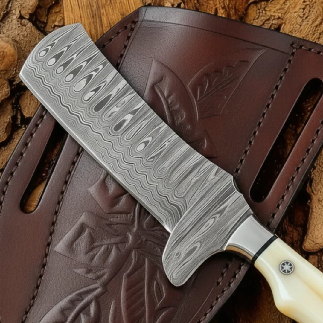 Close-up of Damascus steel blade pattern on Cowboy Bull Cutter Knife resting on leather sheath.
