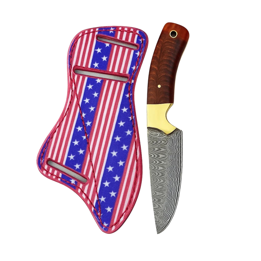Damascus Cowboy Knife with wavy blade pattern and wood handle, resting on a wooden surface with its USA Flag-themed leather sheath nearby.
