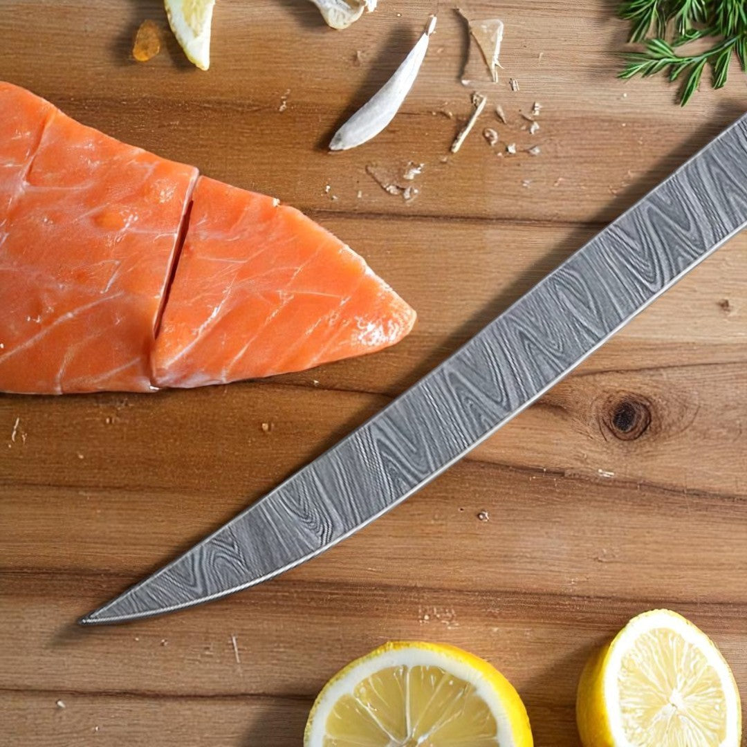 Close-up detail of the Damascus steel blade of a fillet knife, showing its pattern and sharp edge near a salmon fillet on a wooden board