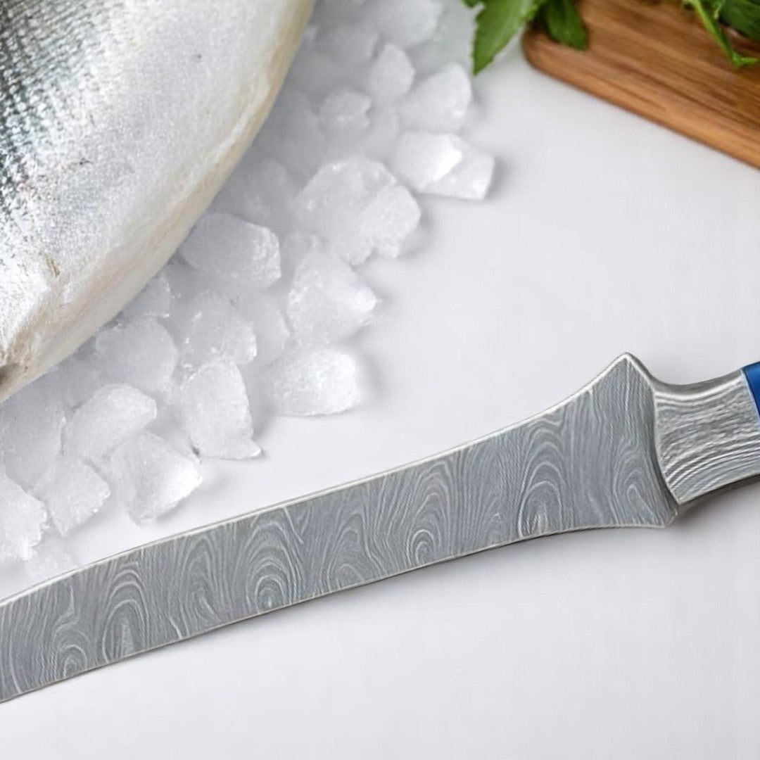 Close-up view of the flexible Damascus steel blade of a fillet knife, showing its wavy pattern and sharp tip near a fish on ice