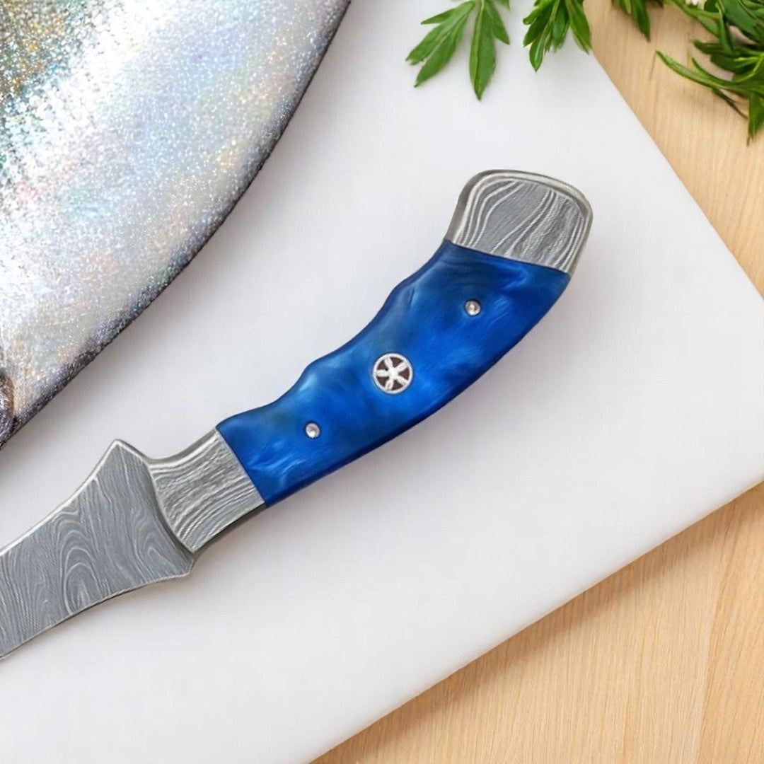  Damascus Fillet Knife with a blue swirled resin handle and Damascus bolster, shown on a white cutting board next to a fish on ice