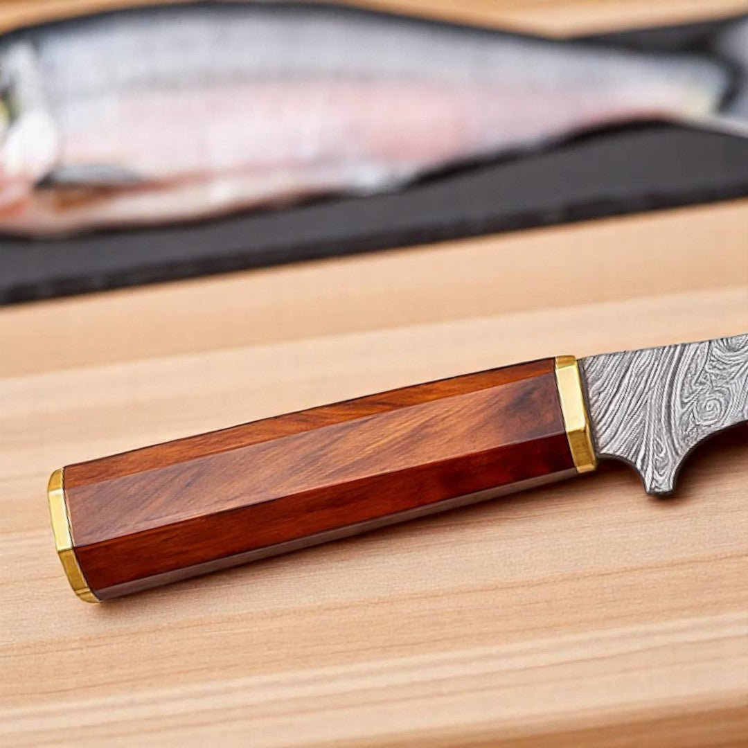 Close-up view of the faceted wood handle with brass bolsters/spacers on a Damascus steel fillet knife, showing its texture and design