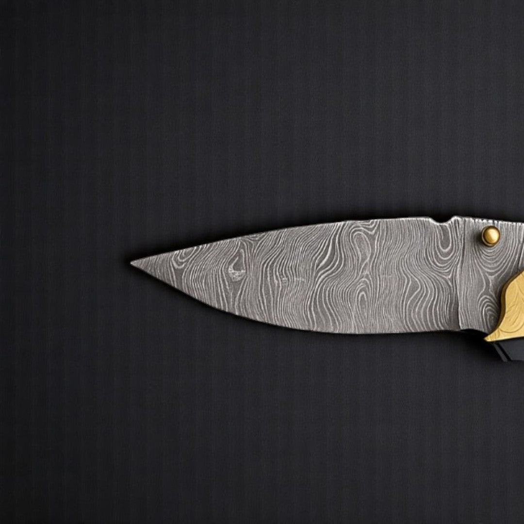 Close-up view of the wavy Damascus steel blade of a Fish-Shaped Folding Knife, highlighting its intricate pattern and sharp point.