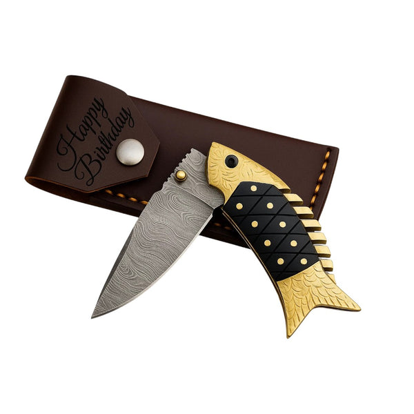 Damascus Fish-Shaped Folding Knife with gold-toned fish handle and wavy Damascus blade, displayed open next to its brown leather sheath on a white background.
