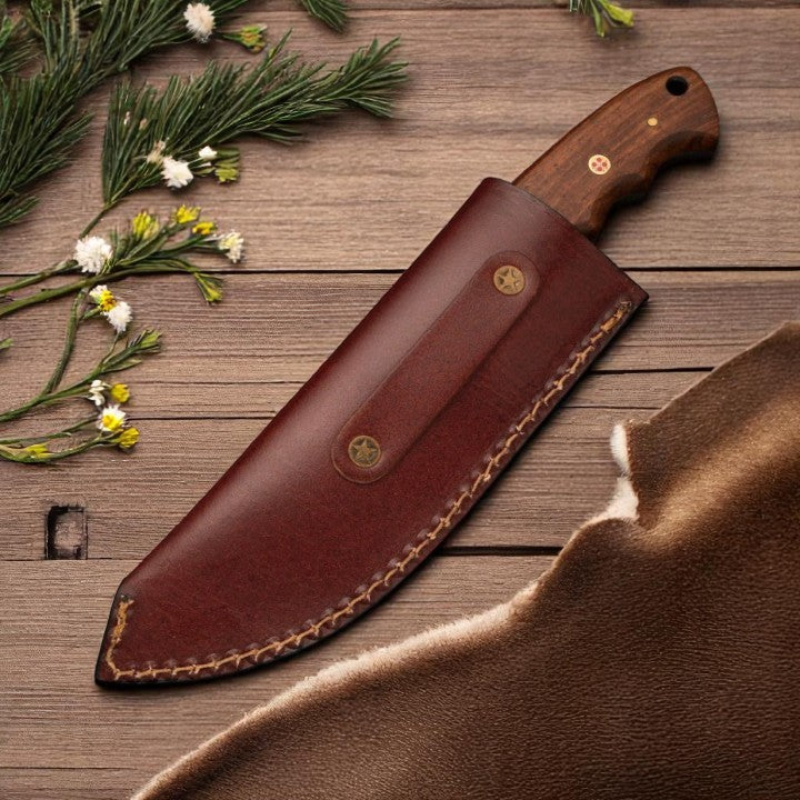 Damascus Gut Hook Skinner Knife with wood handle and gut hook blade, resting next to its brown leather sheath on a wooden surface.