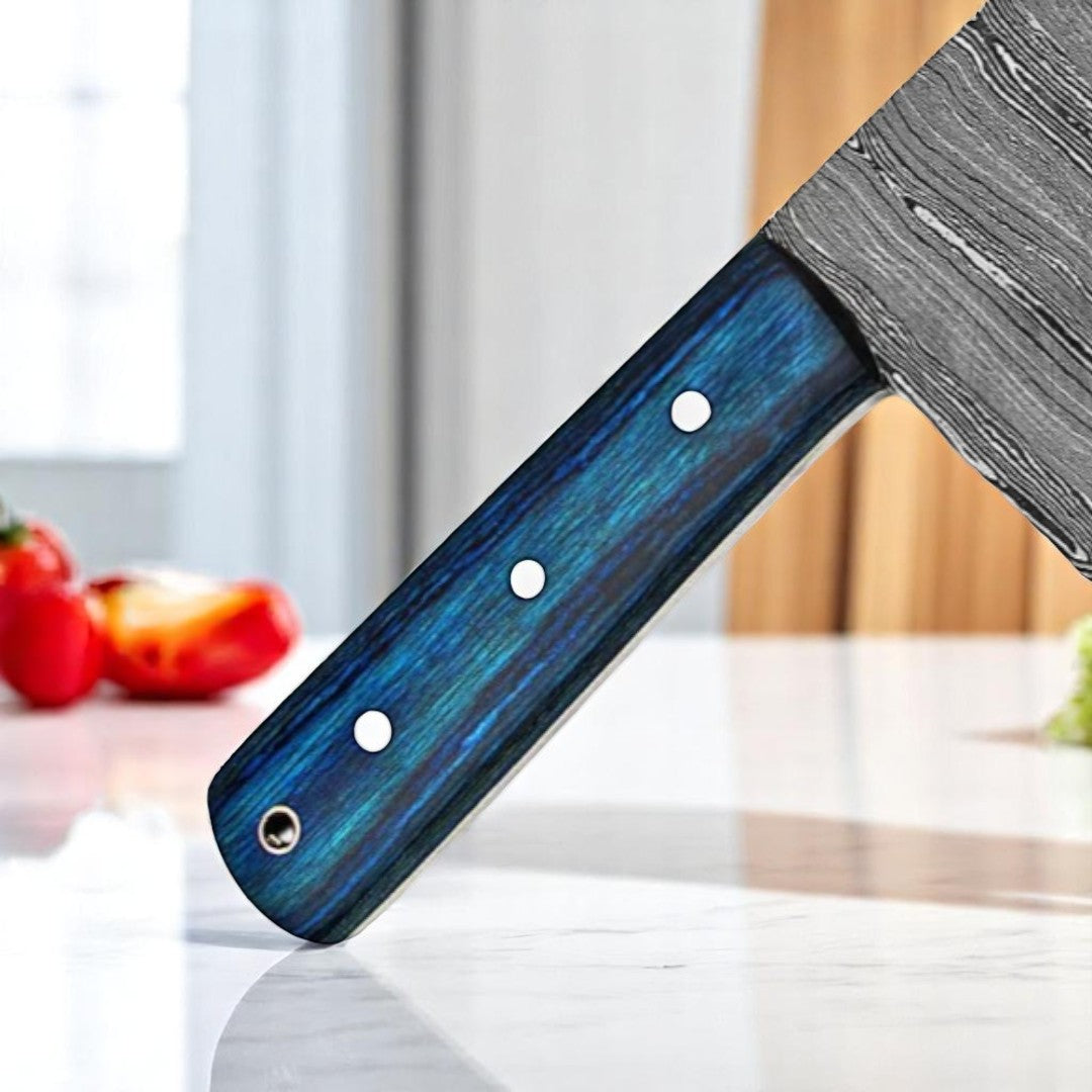 Close-up view of the blue and black swirled handle of a Tactical Damascus Serbian Cleaver Knife, showing rivets and blade pattern