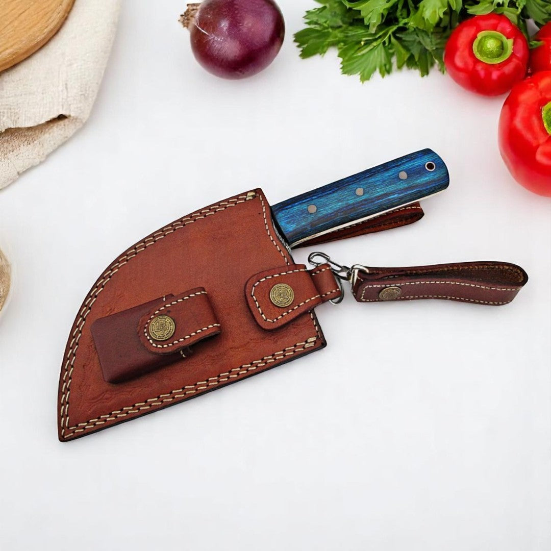 Tactical Damascus Serbian Cleaver Knife in its brown leather sheath with unique attachment system, on a white surface with fresh vegetables