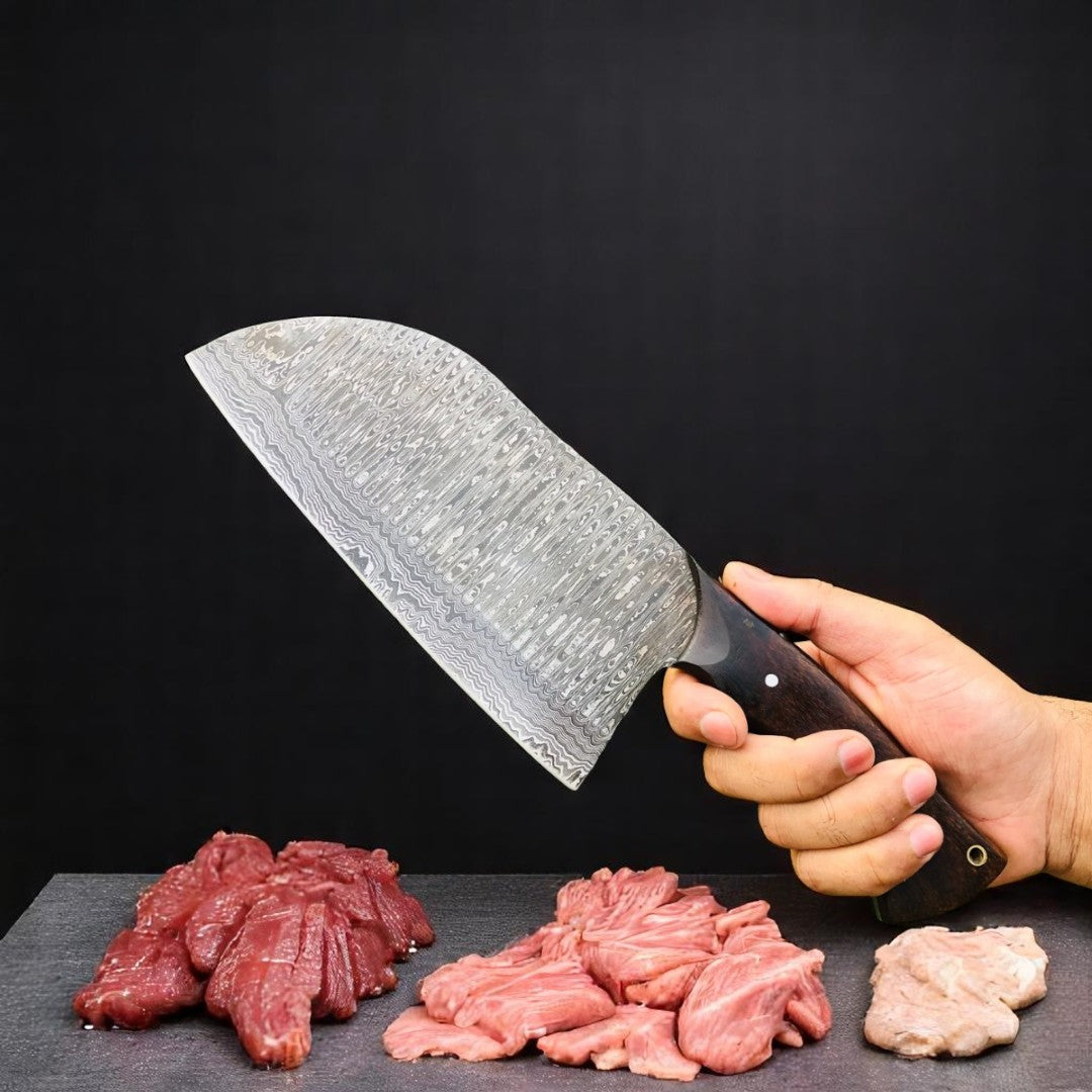 The Butcher's Cleaver Bone Chopper with Damascus steel blade and natural wood handle, held in a hand over raw meat cuts